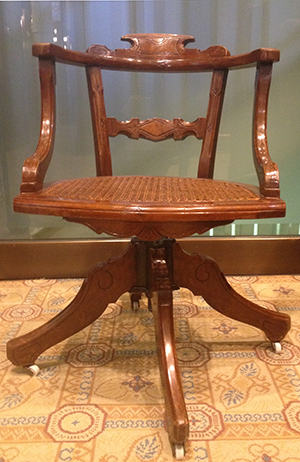 Walnut swivel chair with cane seat.